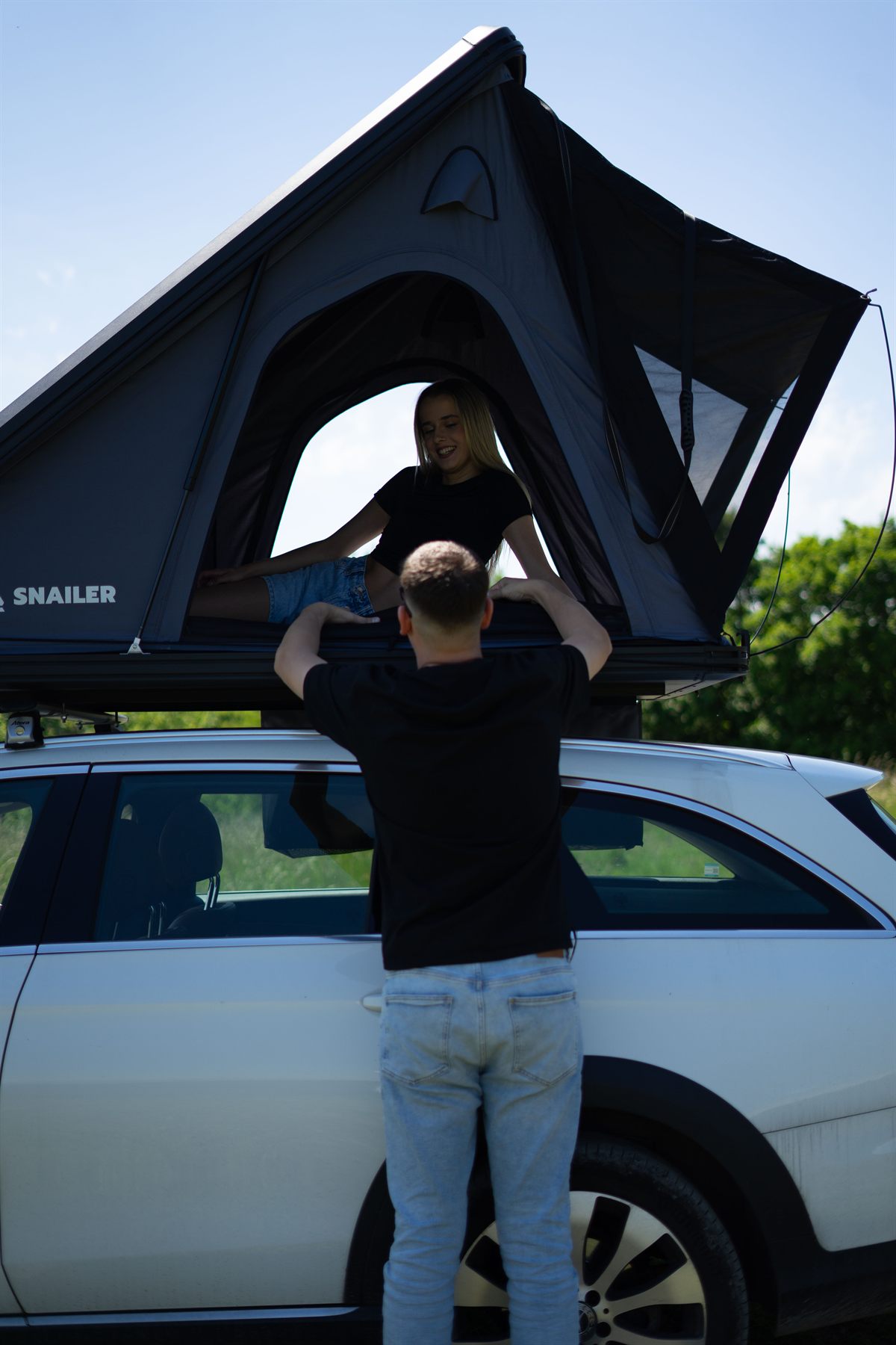Uomo che apre una grande tenda da tetto Snailer sul tetto di un’auto